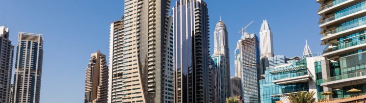 Panorama nowoczesnych wieżowców w Dubaju nad wodą, symbol dynamicznego rynku nieruchomości i inwestowania kapitału w luksusowe apartamenty.
