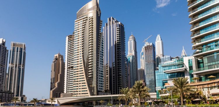 Panorama nowoczesnych wieżowców w Dubaju nad wodą, symbol dynamicznego rynku nieruchomości i inwestowania kapitału w luksusowe apartamenty.