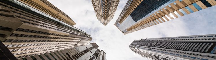 Widok z dołu na nowoczesne wieżowce w Dubaju, symbol dynamicznego rynku nieruchomości i skalowania inwestycji kapitałowych.