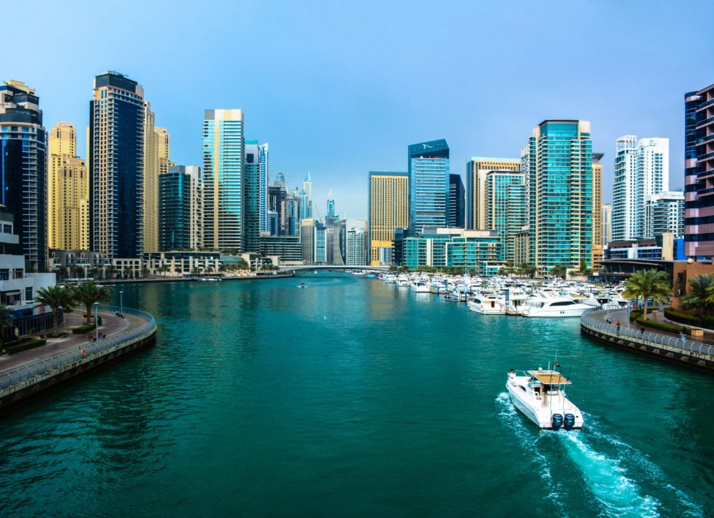 Widok na Dubai Marina z luksusowymi jachtami, nowoczesnymi wieżowcami i turkusową wodą w słoneczny dzień