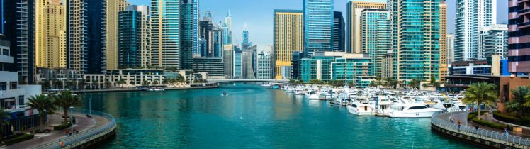 Widok na Dubai Marina z luksusowymi jachtami, nowoczesnymi wieżowcami i turkusową wodą w słoneczny dzień