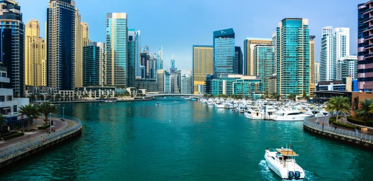 Widok na Dubai Marina z luksusowymi jachtami, nowoczesnymi wieżowcami i turkusową wodą w słoneczny dzień