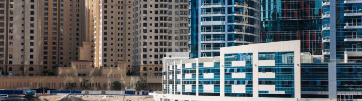 Dubai Marina z turkusowym kanałem, tradycyjną łodzią abra i nowoczesnymi apartamentowcami w tle.