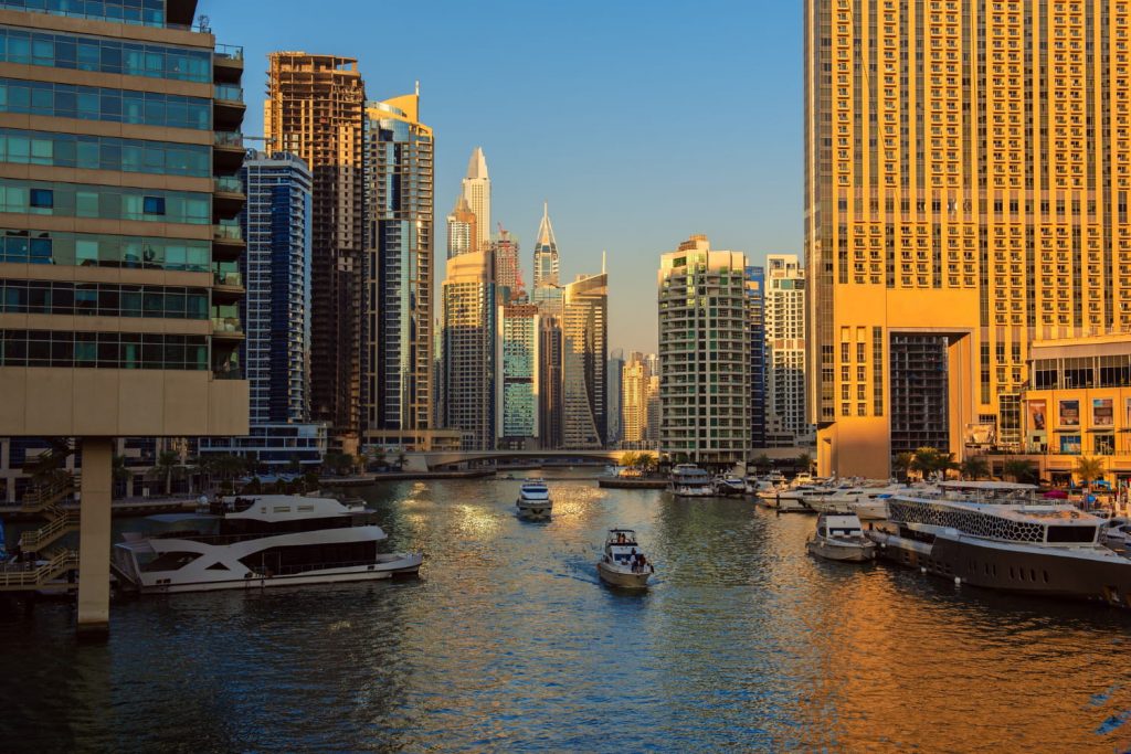 Widok na Dubai Marina o zachodzie słońca z luksusowymi jachtami, kanałem wodnym i nowoczesnymi wieżowcami w tle