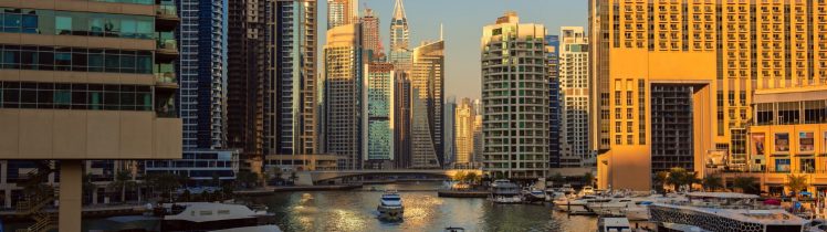 Widok na Dubai Marina o zachodzie słońca z luksusowymi jachtami, kanałem wodnym i nowoczesnymi wieżowcami w tle