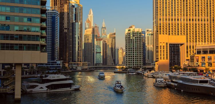 Widok na Dubai Marina o zachodzie słońca z luksusowymi jachtami, kanałem wodnym i nowoczesnymi wieżowcami w tle