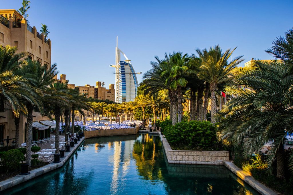 Widok na Madinat Jumeirah z kanałem wodnym, palmami i hotelem Burj Al Arab w tle w słoneczny dzień