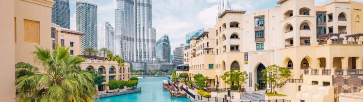 Widok na Downtown Dubai z kanałem wodnym, tradycyjną arabską architekturą, palmami oraz wieżowcem Burj Khalifa w tle.