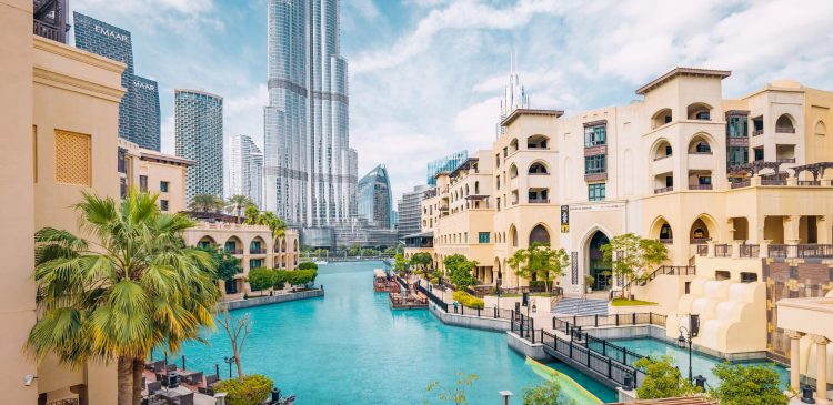 Widok na Downtown Dubai z kanałem wodnym, tradycyjną arabską architekturą, palmami oraz wieżowcem Burj Khalifa w tle.