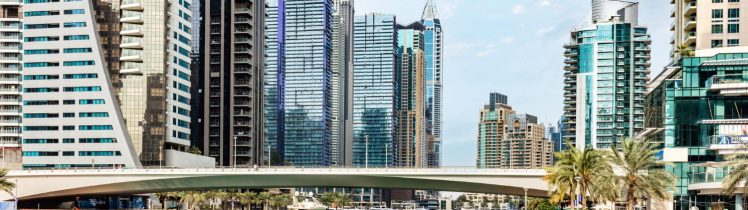 Nowoczesna panorama Dubaju z mariną, mostem nad wodą i wysokimi wieżowcami w tle w słoneczny dzień