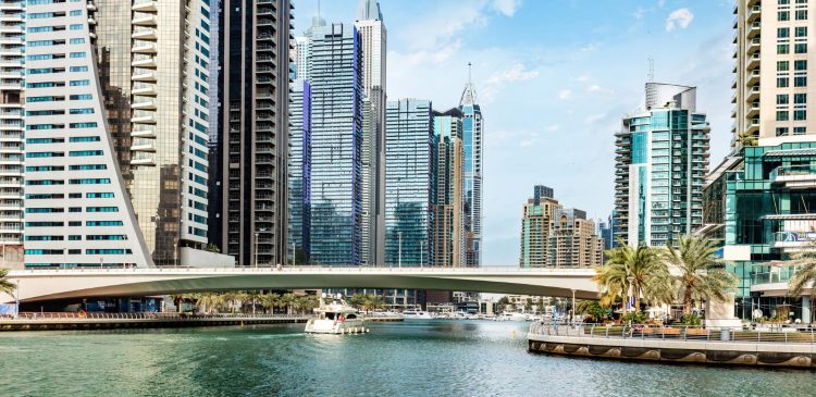 Nowoczesna panorama Dubaju z mariną, mostem nad wodą i wysokimi wieżowcami w tle w słoneczny dzień