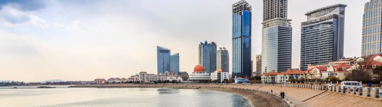 Nadmorska promenada w Ras Al Khaimah z widokiem na spokojne morze, nowoczesne wieżowce i zabudowę miejską w tle.