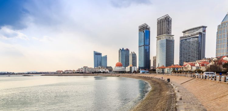 Nadmorska promenada w Ras Al Khaimah z widokiem na spokojne morze, nowoczesne wieżowce i zabudowę miejską w tle.