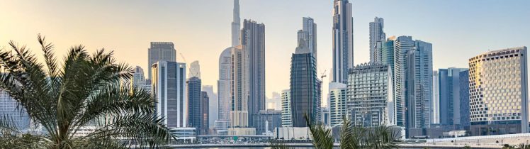 Panorama Dubaju z widokiem na Burj Khalifa, marinę z jachtami oraz nowoczesne wieżowce w tle, otoczone palmami i wodą