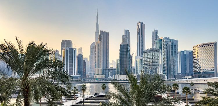 Panorama Dubaju z widokiem na Burj Khalifa, marinę z jachtami oraz nowoczesne wieżowce w tle, otoczone palmami i wodą