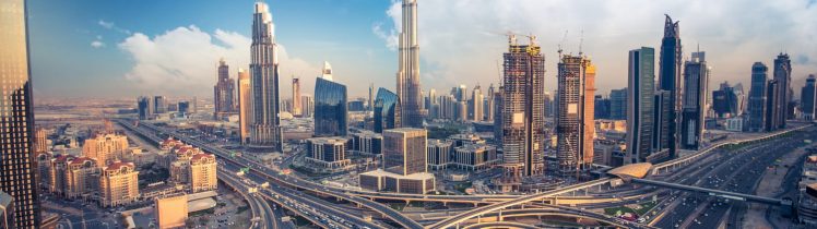 Panorama Dubaju z Burj Khalifa w centrum oraz rozbudowaną siecią autostrad i nowoczesnych wieżowców w słoneczny dzień