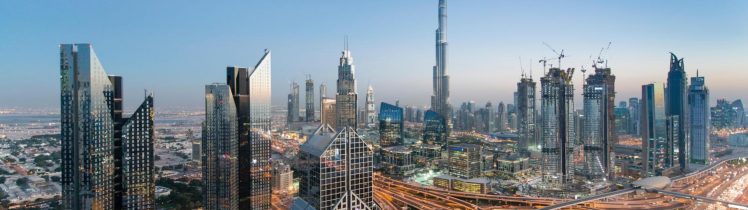 Panorama Dubaju o zmierzchu z widokiem na Burj Khalifa, nowoczesne wieżowce i rozbudowaną infrastrukturę miasta.