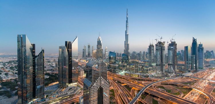 Panorama Dubaju o zmierzchu z widokiem na Burj Khalifa, nowoczesne wieżowce i rozbudowaną infrastrukturę miasta.