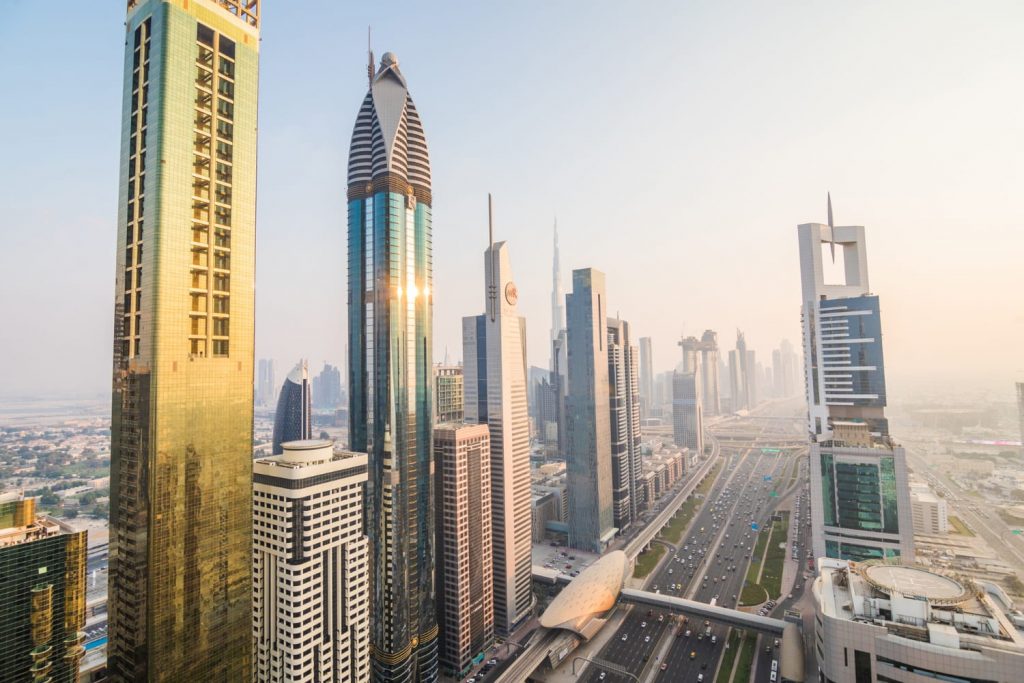 Panorama nowoczesnego centrum Dubaju z wieżowcami przy Sheikh Zayed Road i widokiem na Burj Khalifa o zachodzie słońca.