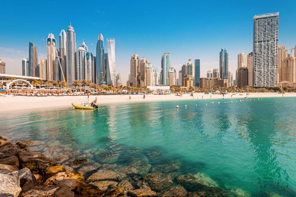 Plaża w Dubaju z widokiem na nowoczesne wieżowce Dubai Marina i turkusowe wody Zatoki Perskiej.