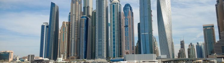 Nowoczesne wieżowce Dubai Marina i panorama luksusowej dzielnicy nad wodą w słoneczny dzień.