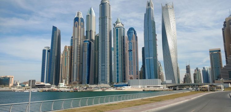 Nowoczesne wieżowce Dubai Marina i panorama luksusowej dzielnicy nad wodą w słoneczny dzień.