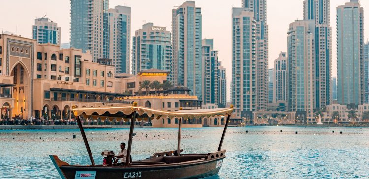 Tradycyjna łódź abra na wodach Dubai Downtown z widokiem na nowoczesne wieżowce i zabudowę w tle.