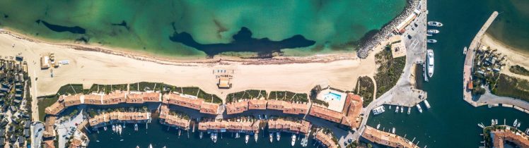 Widok z lotu ptaka na luksusową marinę i plażę w Ras Al Khaimah z turkusową wodą Zatoki Arabskiej
